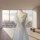 Elegant silver evening gown with intricate detailing on a mannequin against a neutral background.