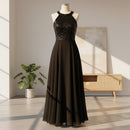 Woman wearing a black evening gown with sequin top in a fitting room.