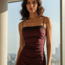 Burgundy strapless gown with a high slit on a light blue background