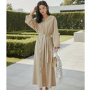 Woman in a beige trench coat holding an umbrella in a modern interior setting