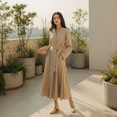 Woman in a beige dress standing in a modern kitchen.