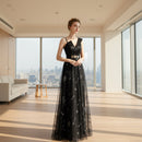 Woman wearing a black evening gown with floral embroidery on a white background