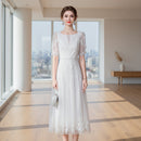 Woman wearing a white lace dress against a gray background