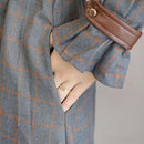 Gray checkered coat with a brown leather pocket on a neutral background