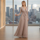 Woman wearing a long, flowing dress in a room with white walls and a small table.