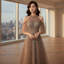 Woman in a brown evening gown with intricate detailing in a dimly lit room.