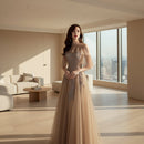 Woman wearing a glamorous evening gown with intricate detailing against a dark background