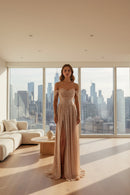 Elegant off-shoulder gown with a high slit on a gray background