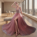 Woman in a pink evening gown with a high slit standing in a bright room.
