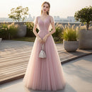 Woman in a pink evening gown holding a fan against a gray textured wall