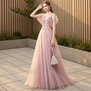 Woman in a pink evening gown against a textured gray wall