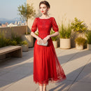 Woman wearing a red dress with lace details against a gray background