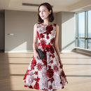 Woman wearing a red and white floral dress against a light background